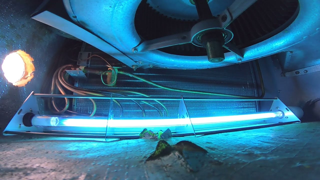 A glowing blue UV light inside an air conditioning unit with visible wiring and a fan above, ensuring cleaner Fresh Air Ducts for optimal indoor air quality in MD.