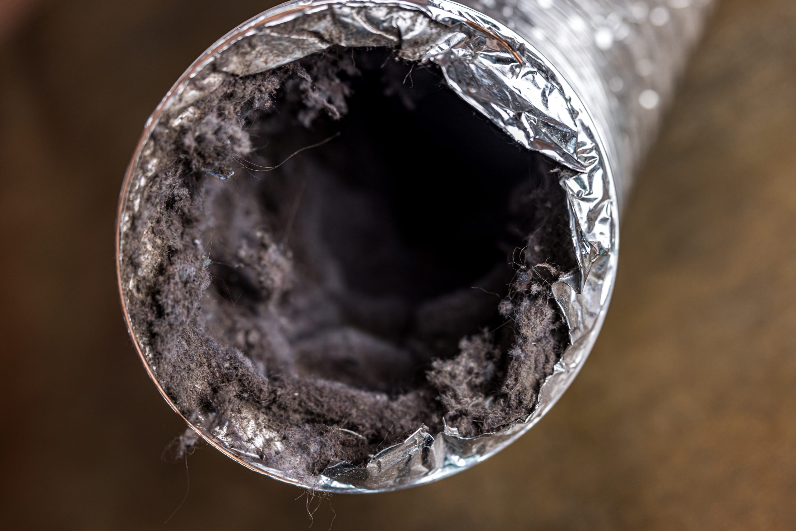 Close-up of a dryer vent clogged with lint and dust, showing potential fire hazard.